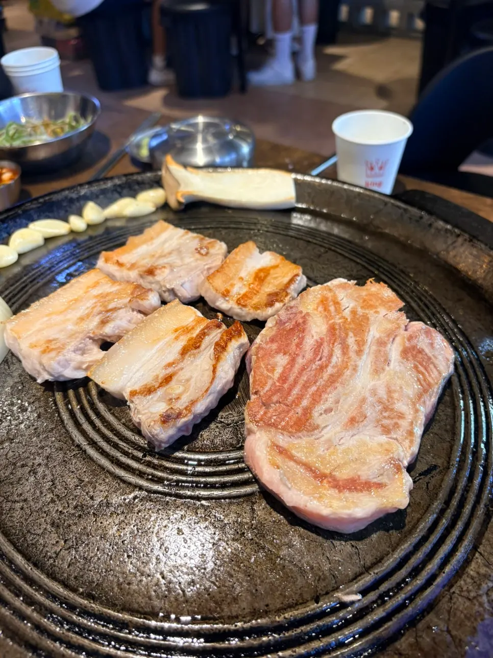 직원이 솥뚜껑에 고기를 구워주는 모습