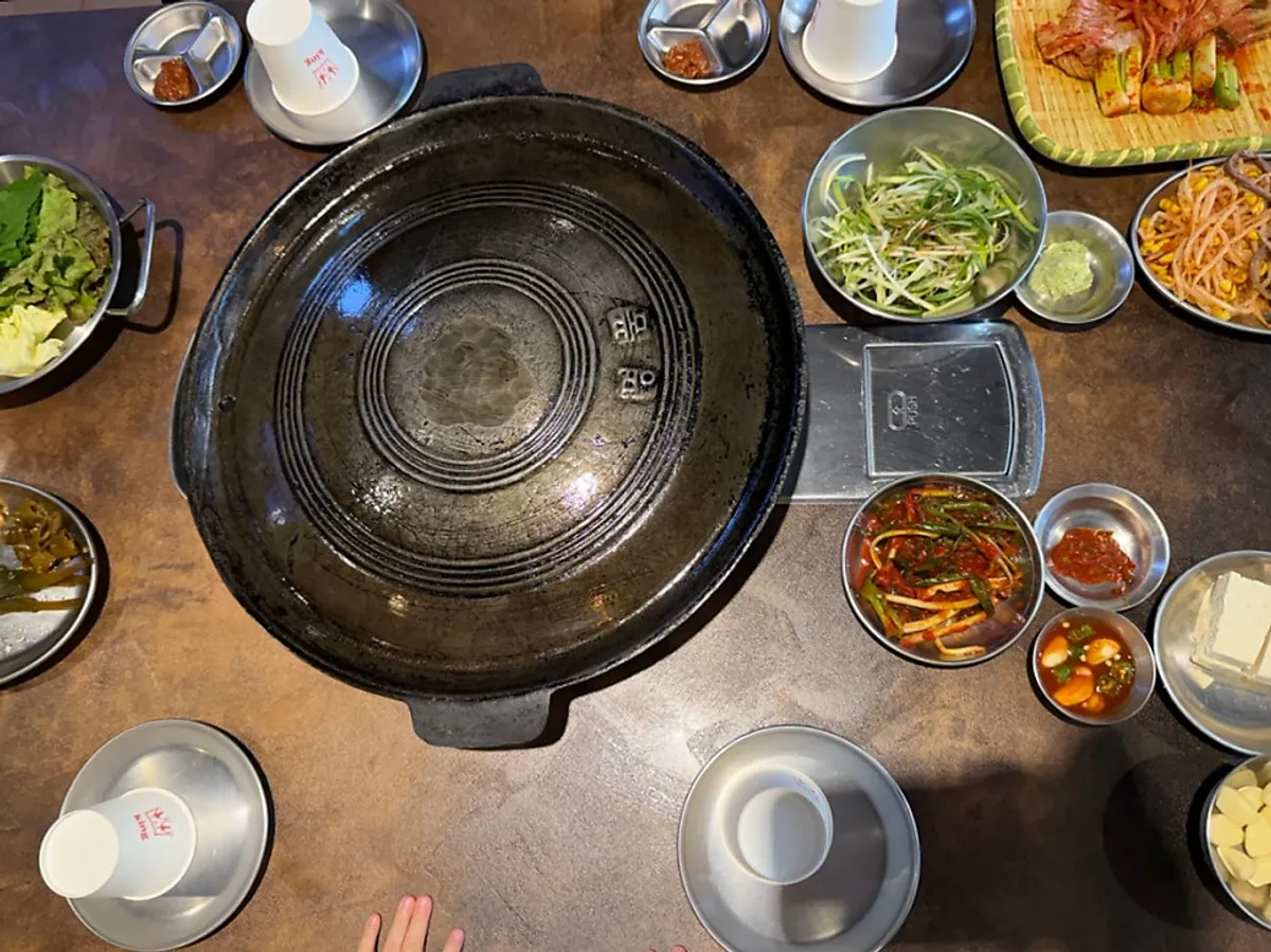 Kimchi, bean sprouts, garlic, and ogyeopsal on the cauldron lid