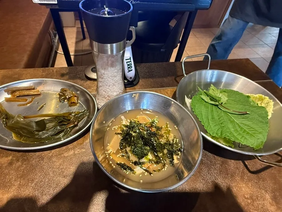 Kimchi and vegetables placed on the edge of the cauldron lid