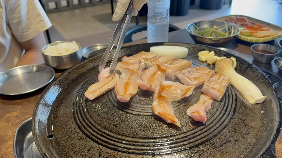 Pork belly grilling to a golden brown on the cauldron lid