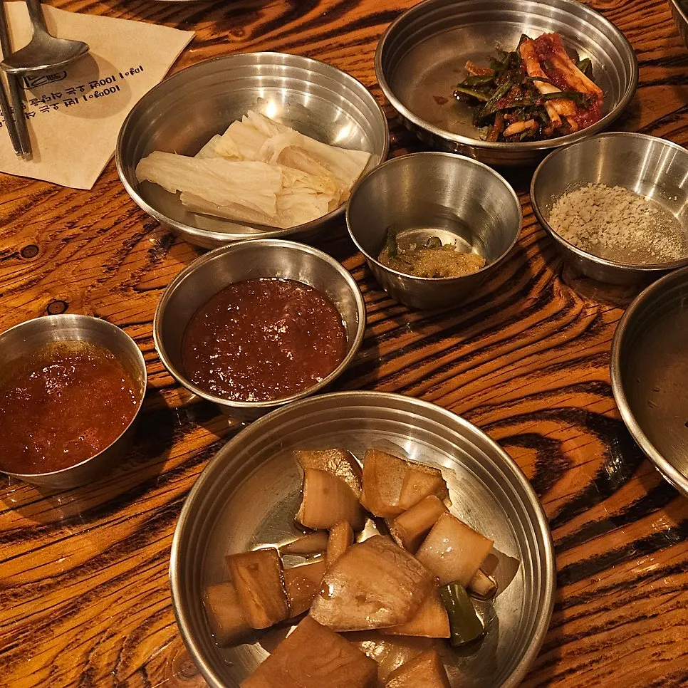 Side dishes including white kimchi and green onion kimchi set on the table