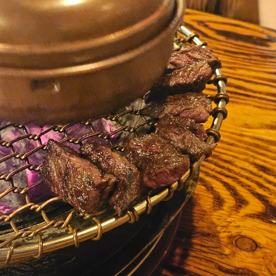 Grilled meat lined up along the edge of the grill