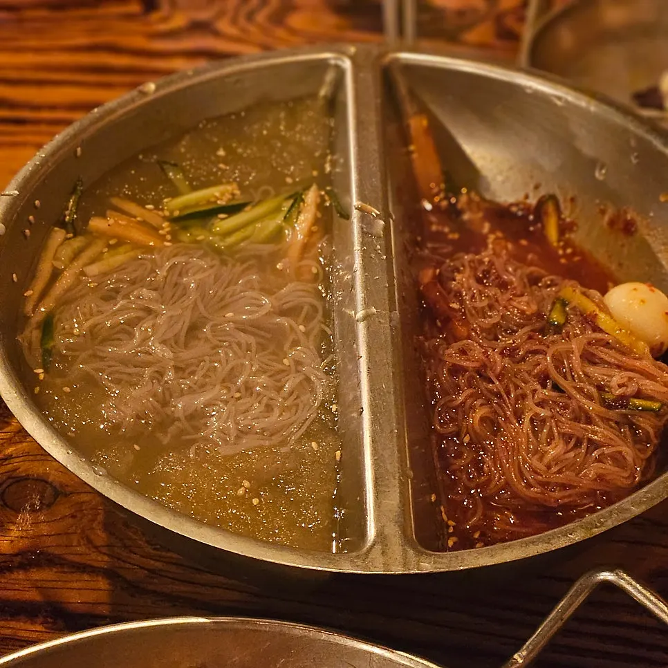 Bowls of red-seasoned bibim naengmyeon and cool water naengmyeon