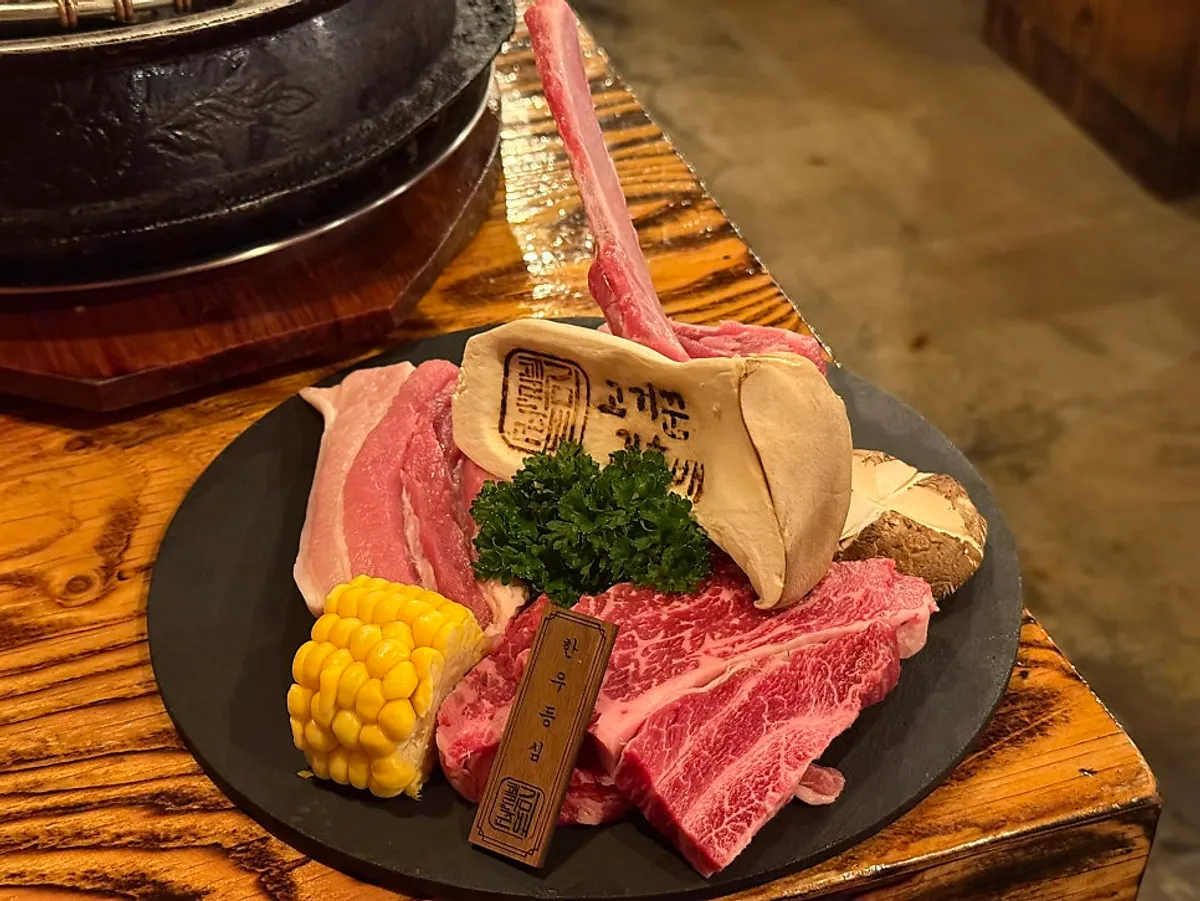 A plate of hanwoo sirloin, pork belly, and mushrooms from the set for two