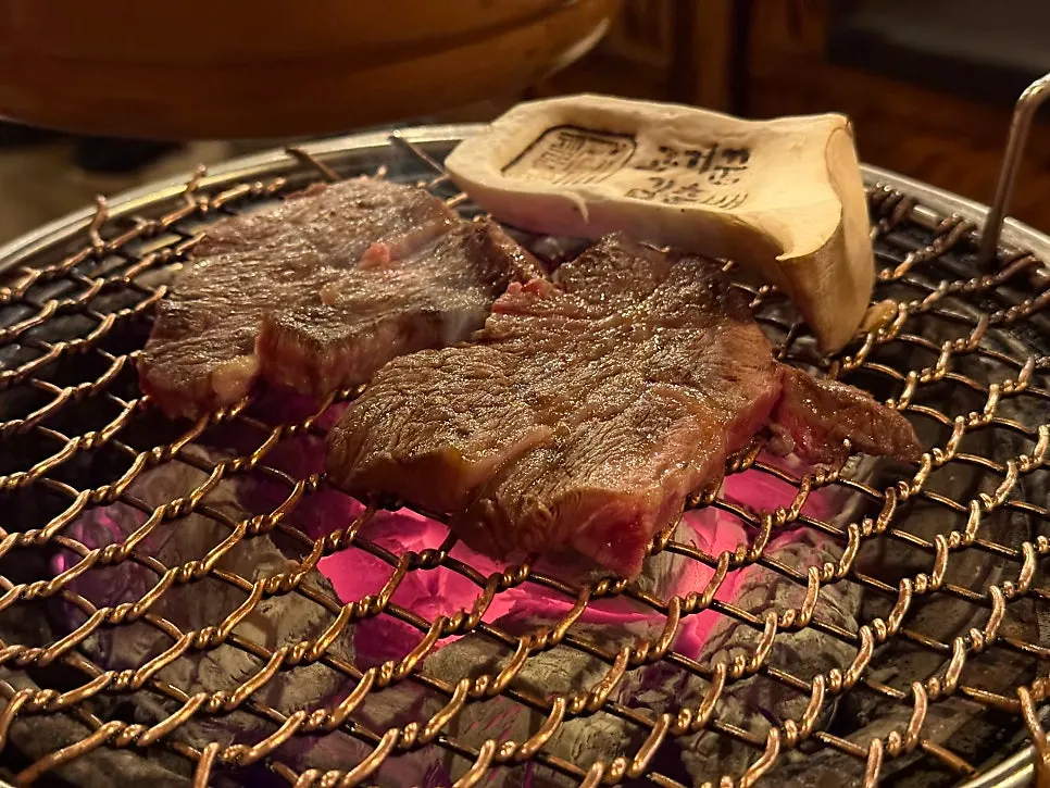 A staff member grilling beef and mushrooms first on the grill