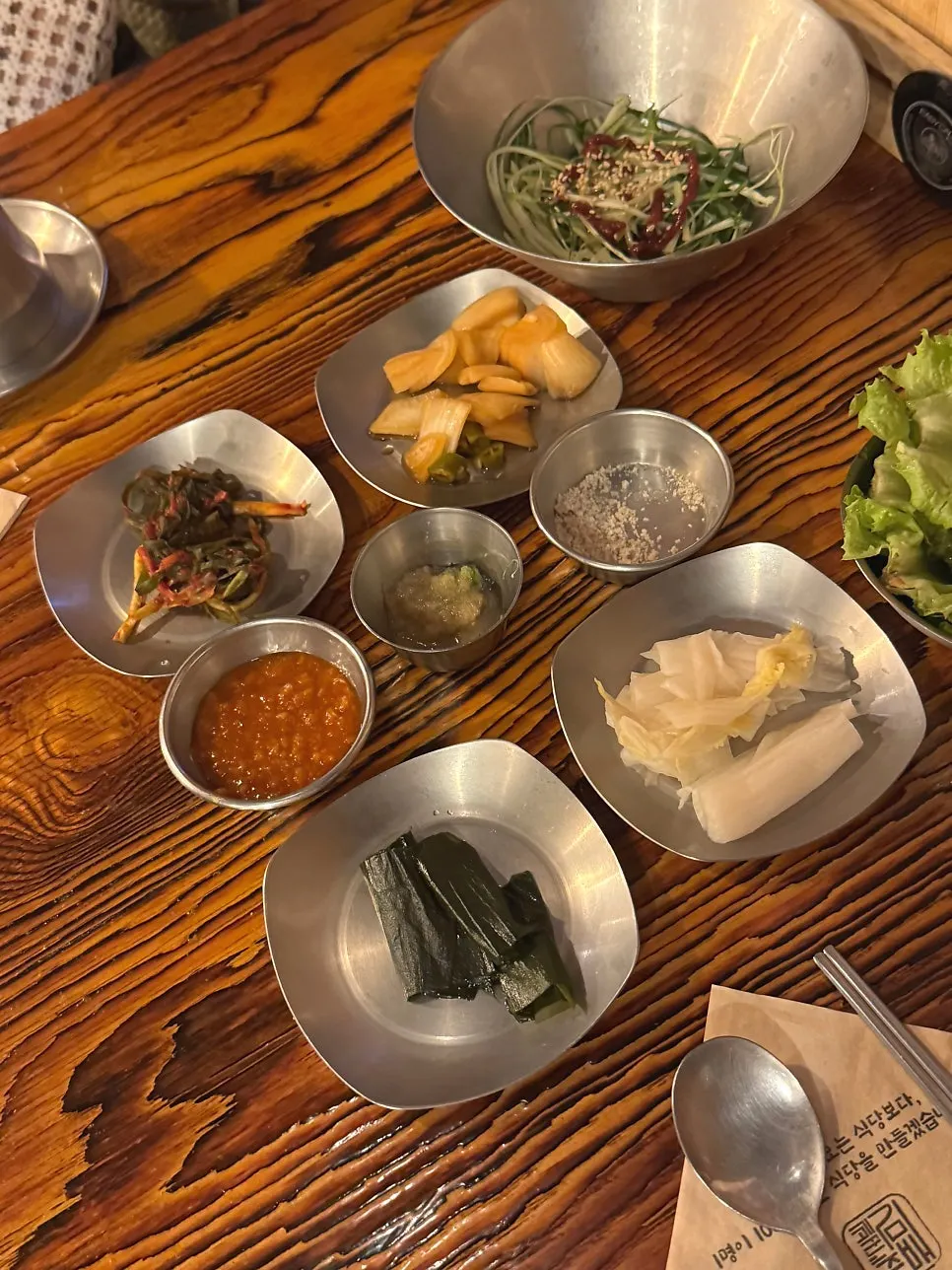 Table spread of basic side dishes including scallion kimchi and white kimchi