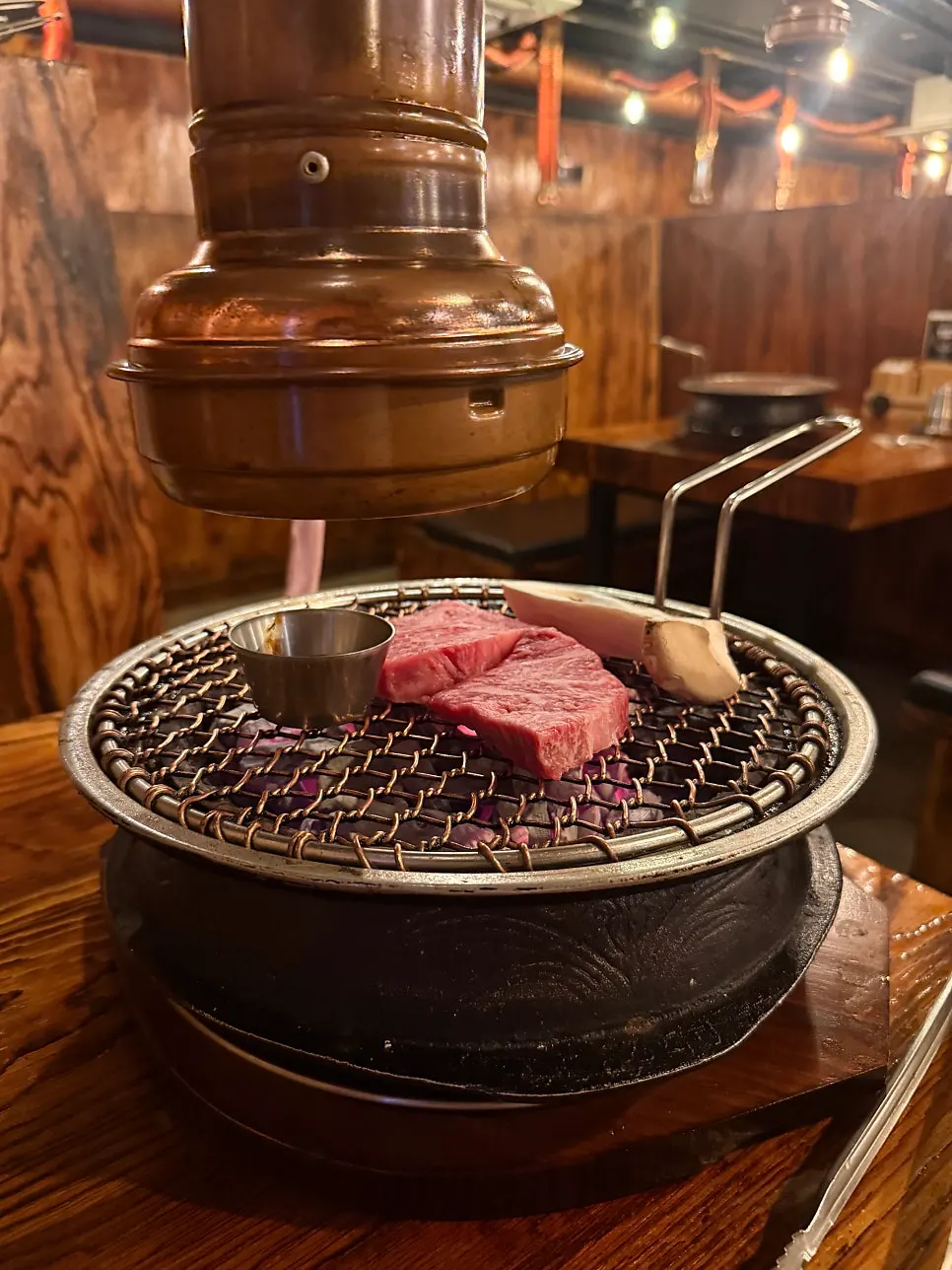 Hanwoo sirloin grilling over charcoal with salted shrimp sauce