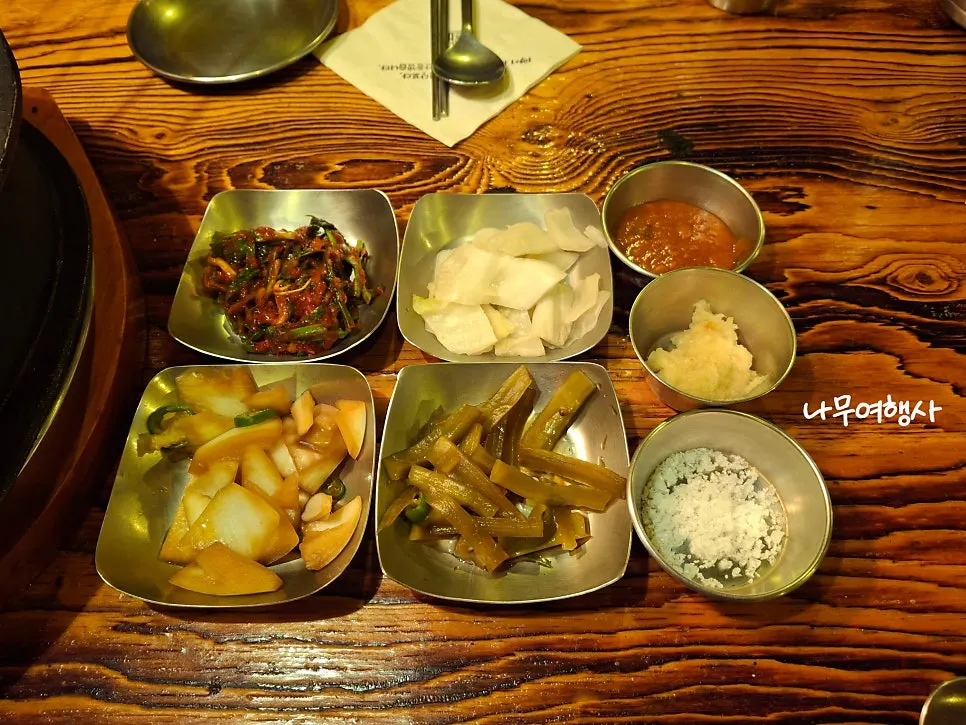 Side dishes including green onion kimchi, white kimchi, pickled onion, and sauces