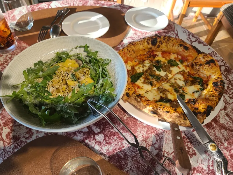 Salsiccia pizza and pasta placed together on the table