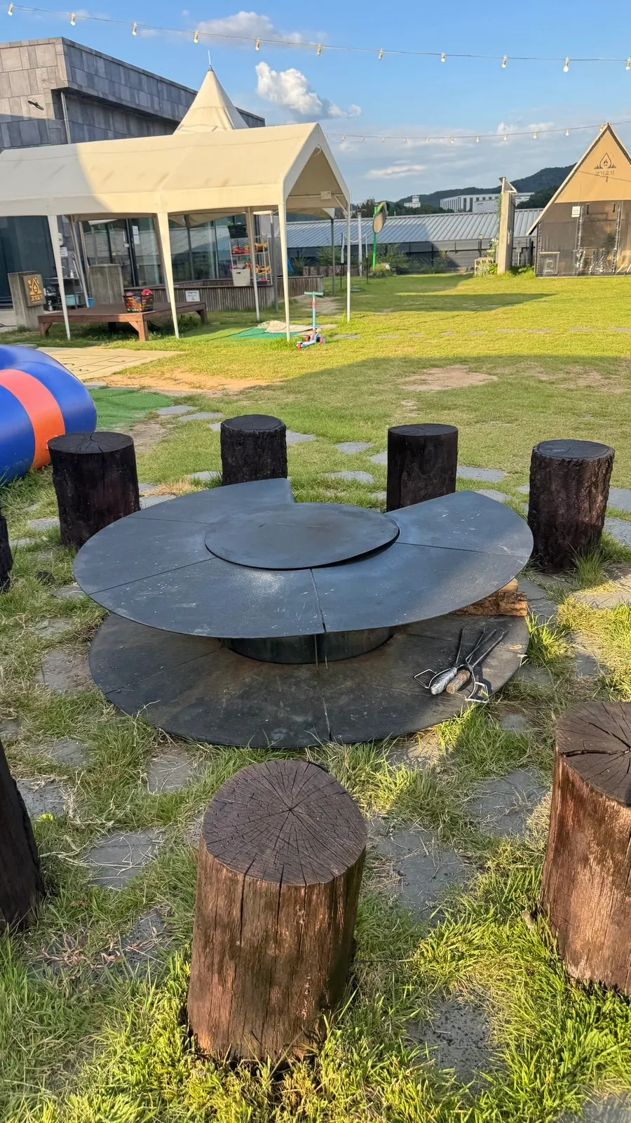 A tent BBQ setup with charcoal and grill ready
