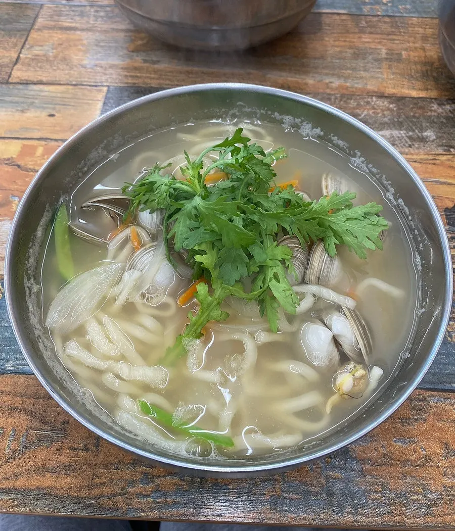 A bowl of Gogo Kalguksu topped with clams