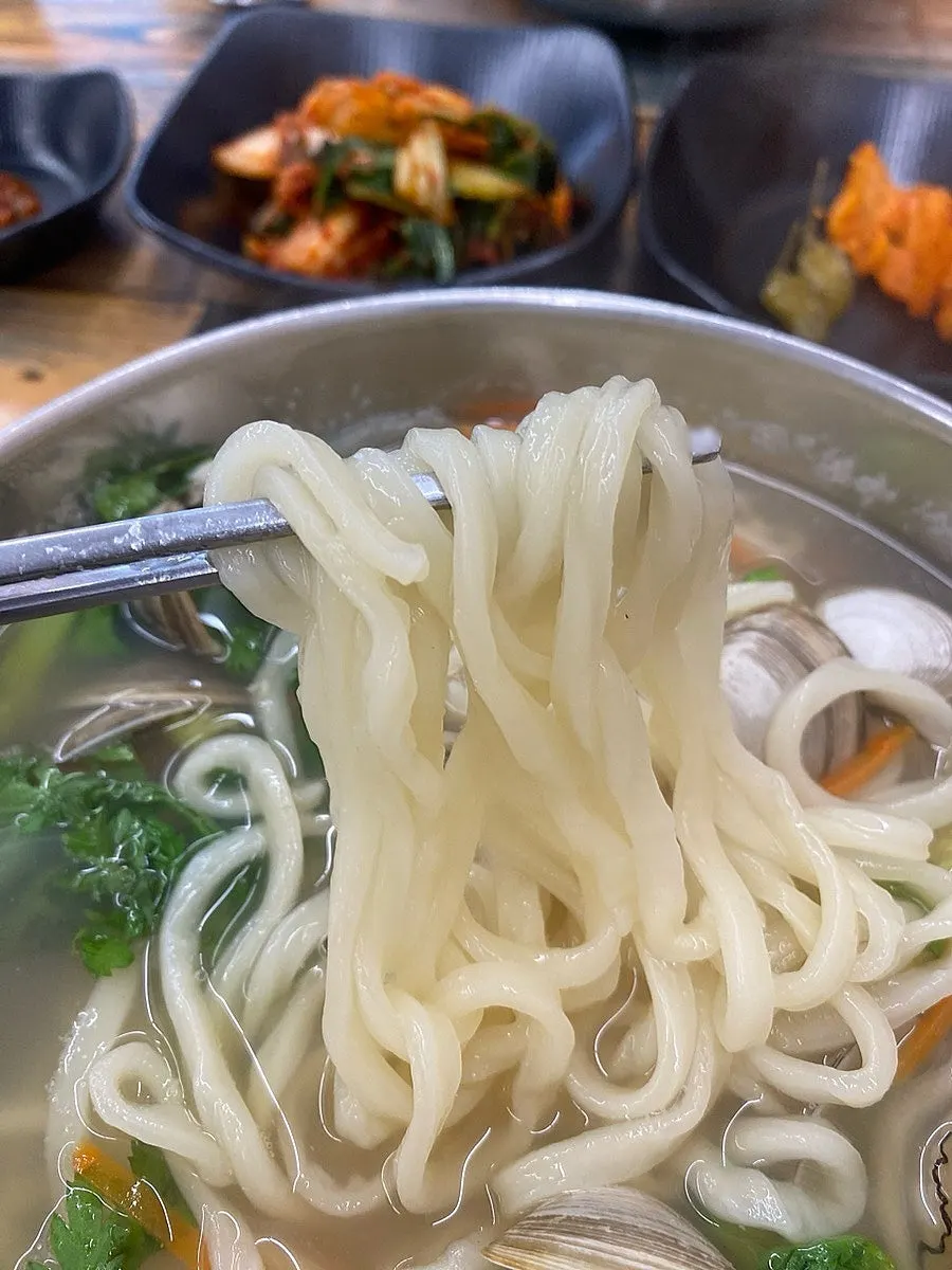 Chewy kalguksu noodles lifted with chopsticks