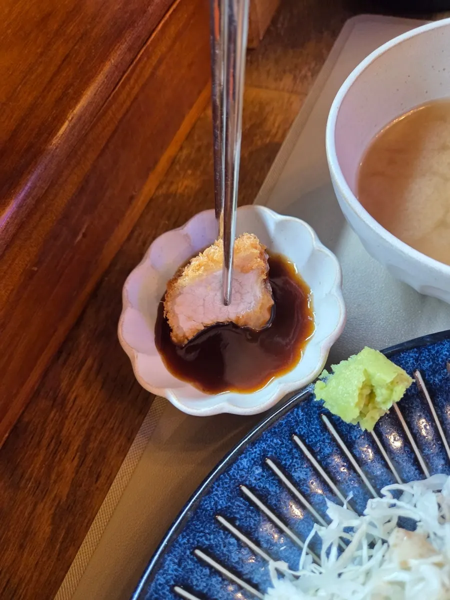 젓가락으로 집어 소스에 찍은 히레카츠 한 점