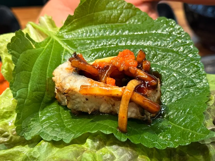 A glass of bokbunja wine next to grilled eel