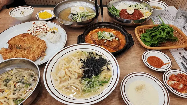 Table full of pork cutlets and noodle dishes