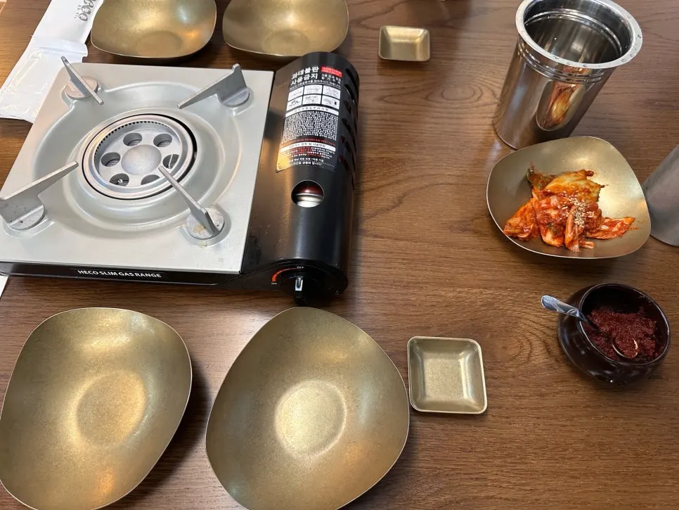 Basic table setup with burner, small plates, kimchi, and dadaegi