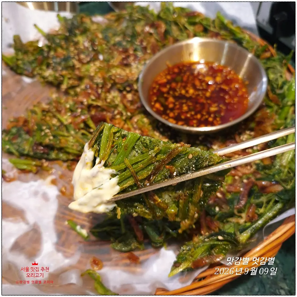 A crispy piece of the barley shrimp minari pancake torn off with chopsticks