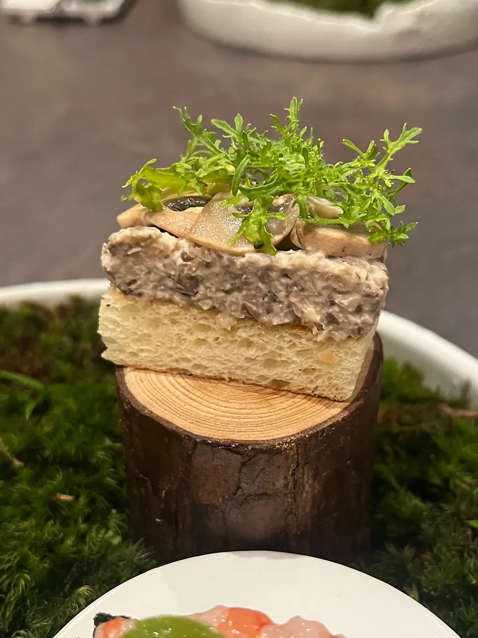 Three bite-sized dishes plated on moss and basalt