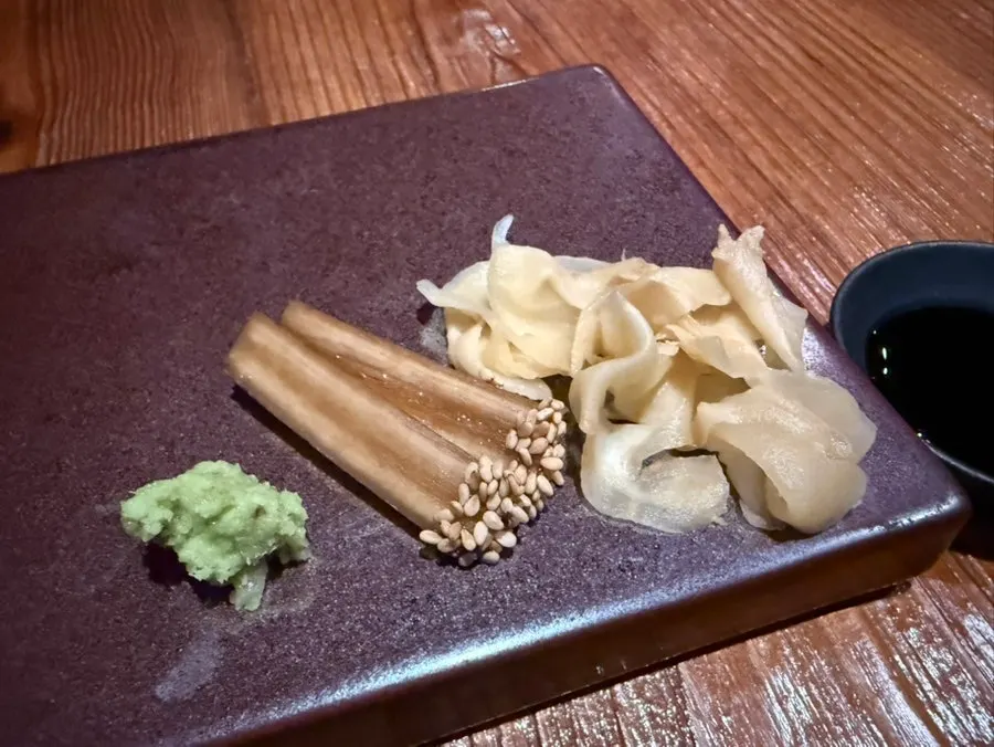 Table setting with wasabi, braised burdock root, pickled ginger, and soy sauce