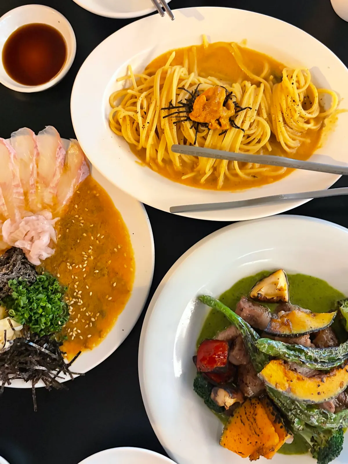 Table spread with ordered sashimi, pasta, and grilled pork collar