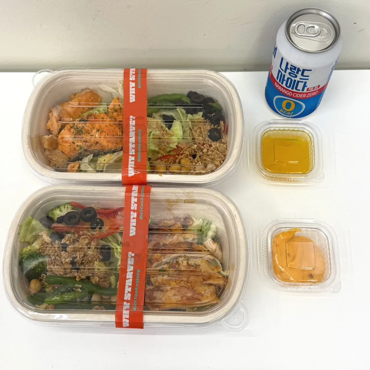 Two protein boxes wrapped tightly in plastic wrap for takeout