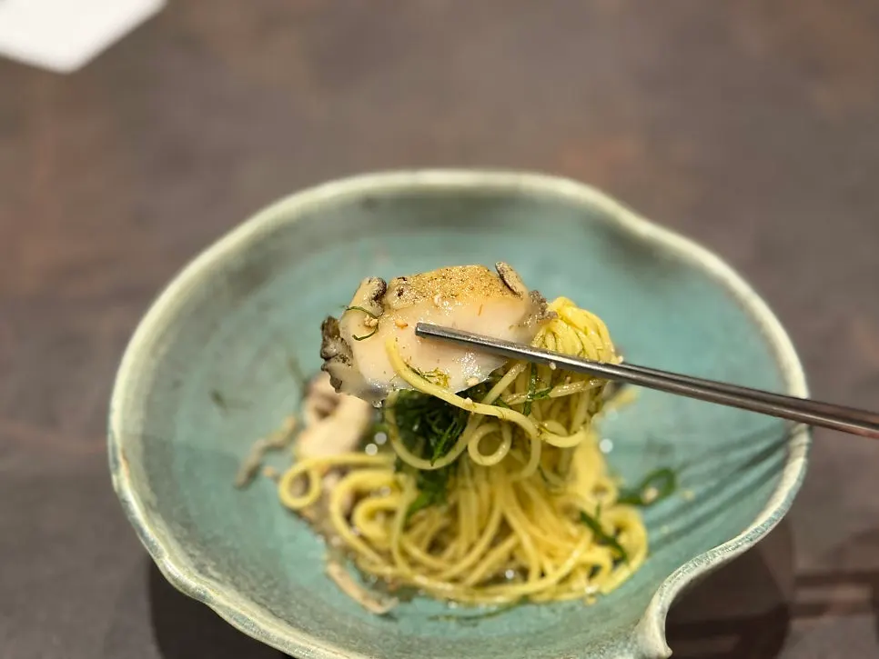 Mixing abalone and greens into the noodles