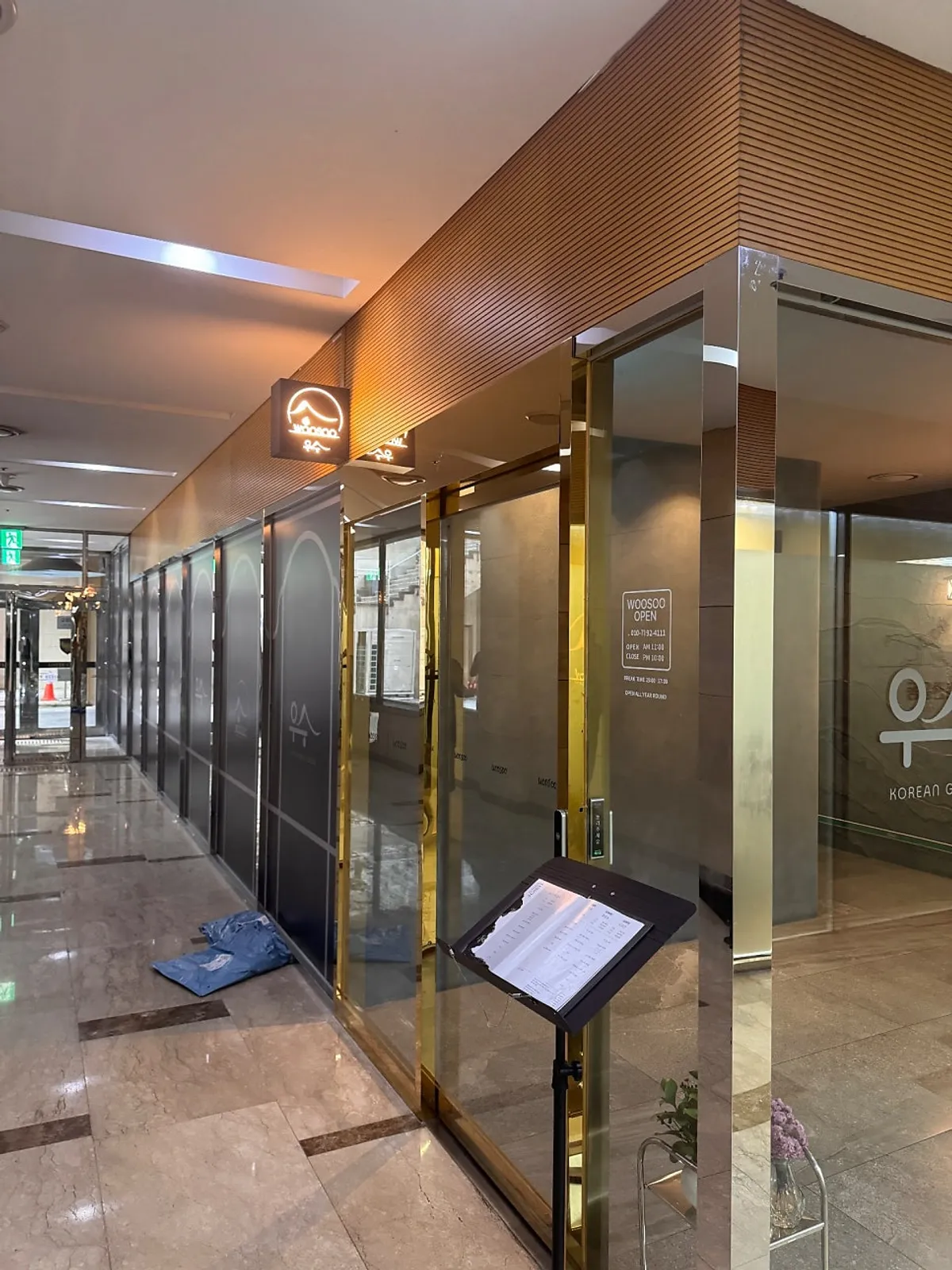 Full view of the Usu entrance with gold-lit signage and stone wall