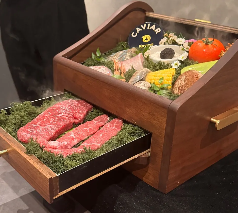 Box of hanwoo, abalone, and caviar ingredients amid dry-ice smoke