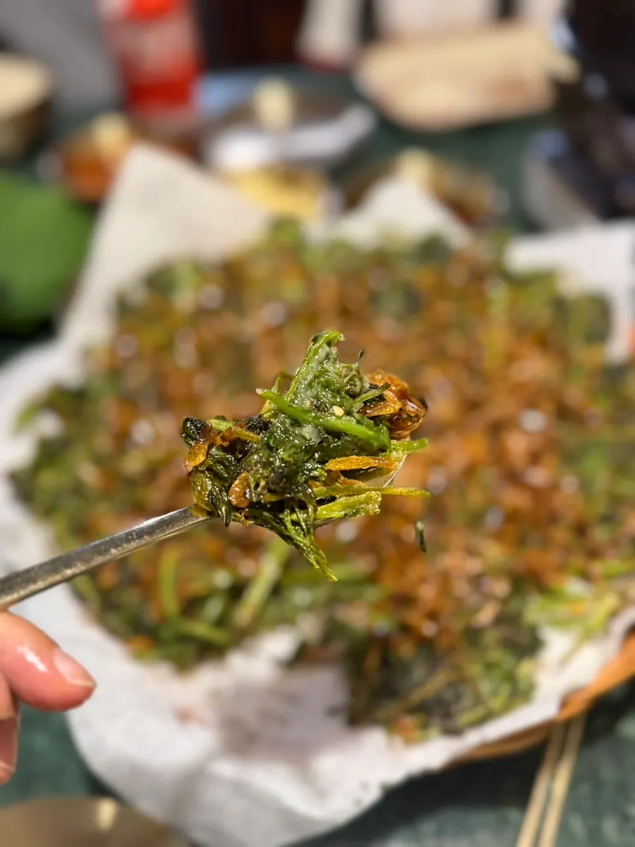 Close-up of the minari pancake piled with barley shrimp