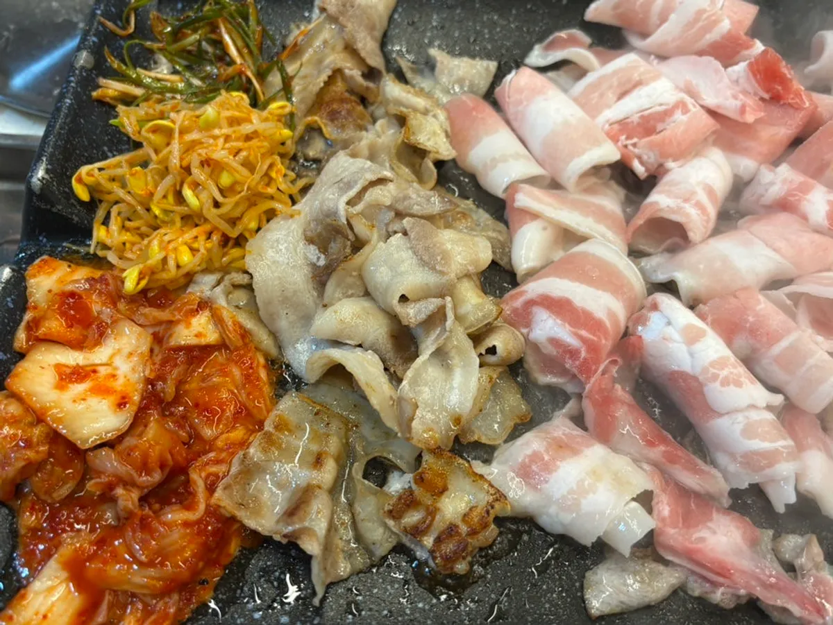 Thinly sliced pork and shredded scallions grilling on the pan