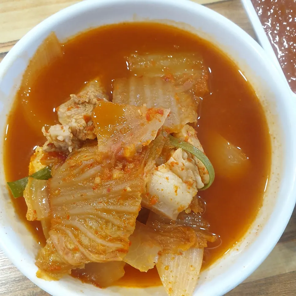앞접시에 덜어 담은 김치찌개 국물과 돼지고기