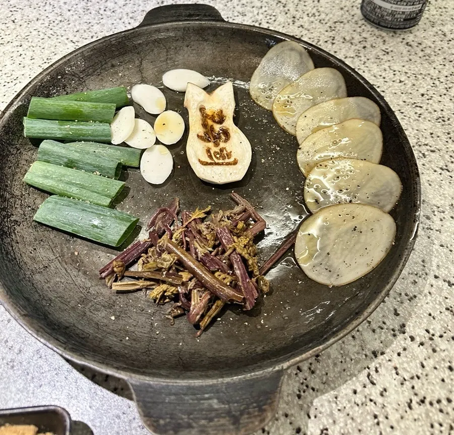 Side dish setup with bracken fern, scallions, garlic, and king oyster mushrooms