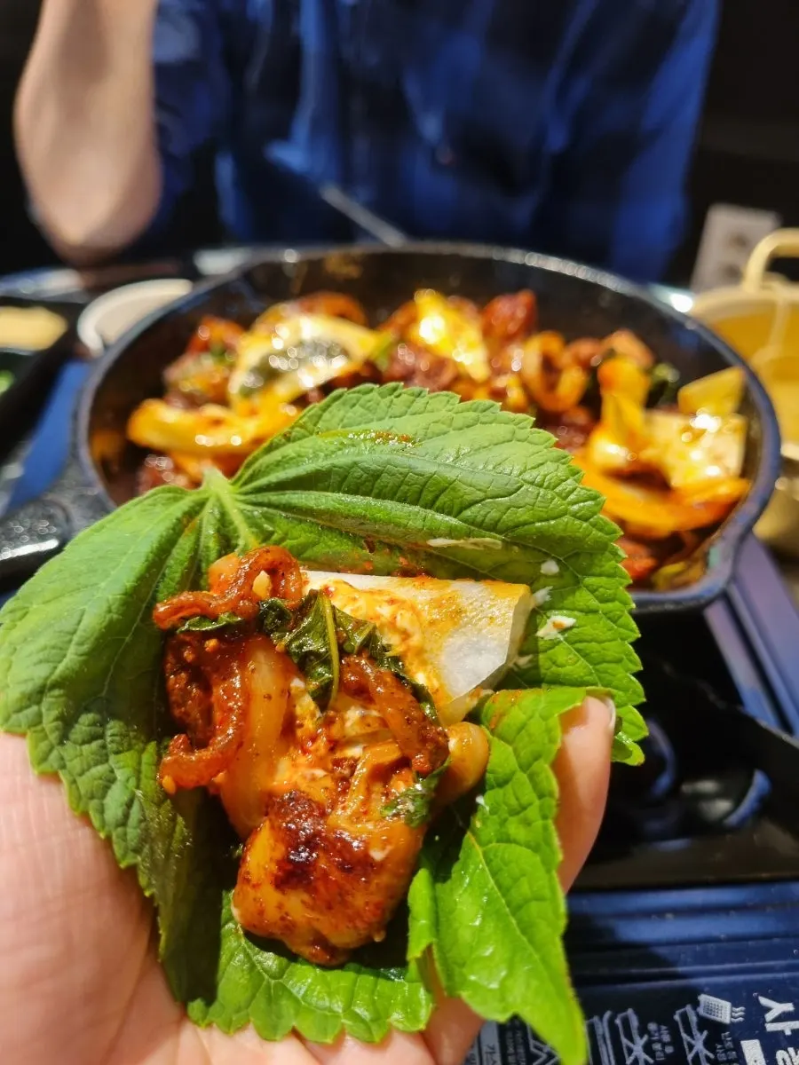 A perilla leaf wrap topped with pickled radish and dipped in sauce