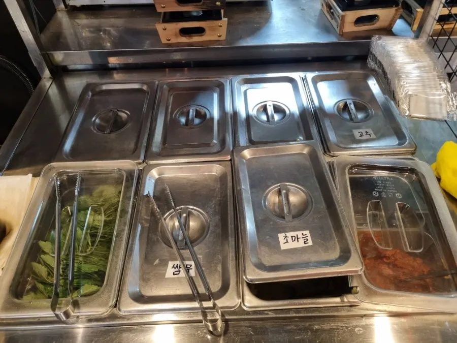 Side dishes of perilla leaves, pickled radish, garlic in vinegar, chili peppers, and doenjang