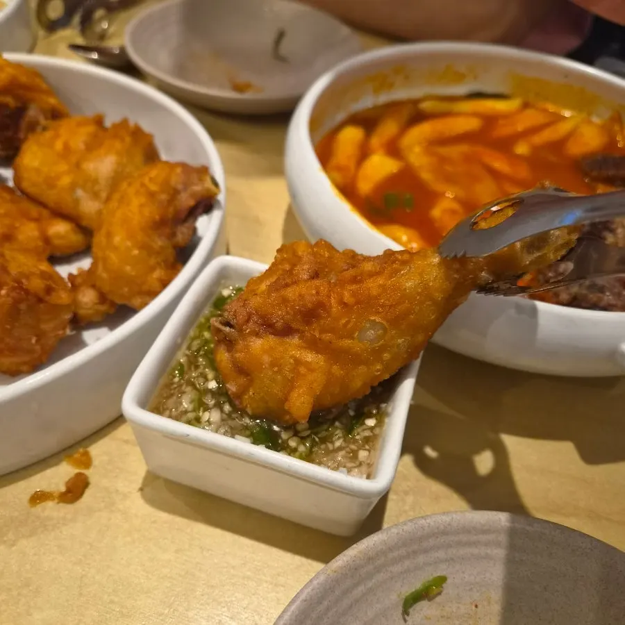 A piece of chicken dipped in sauce