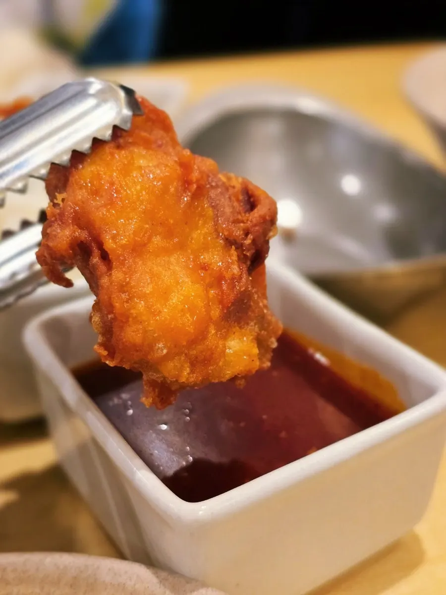 A piece of boneless chicken dipped in sauce