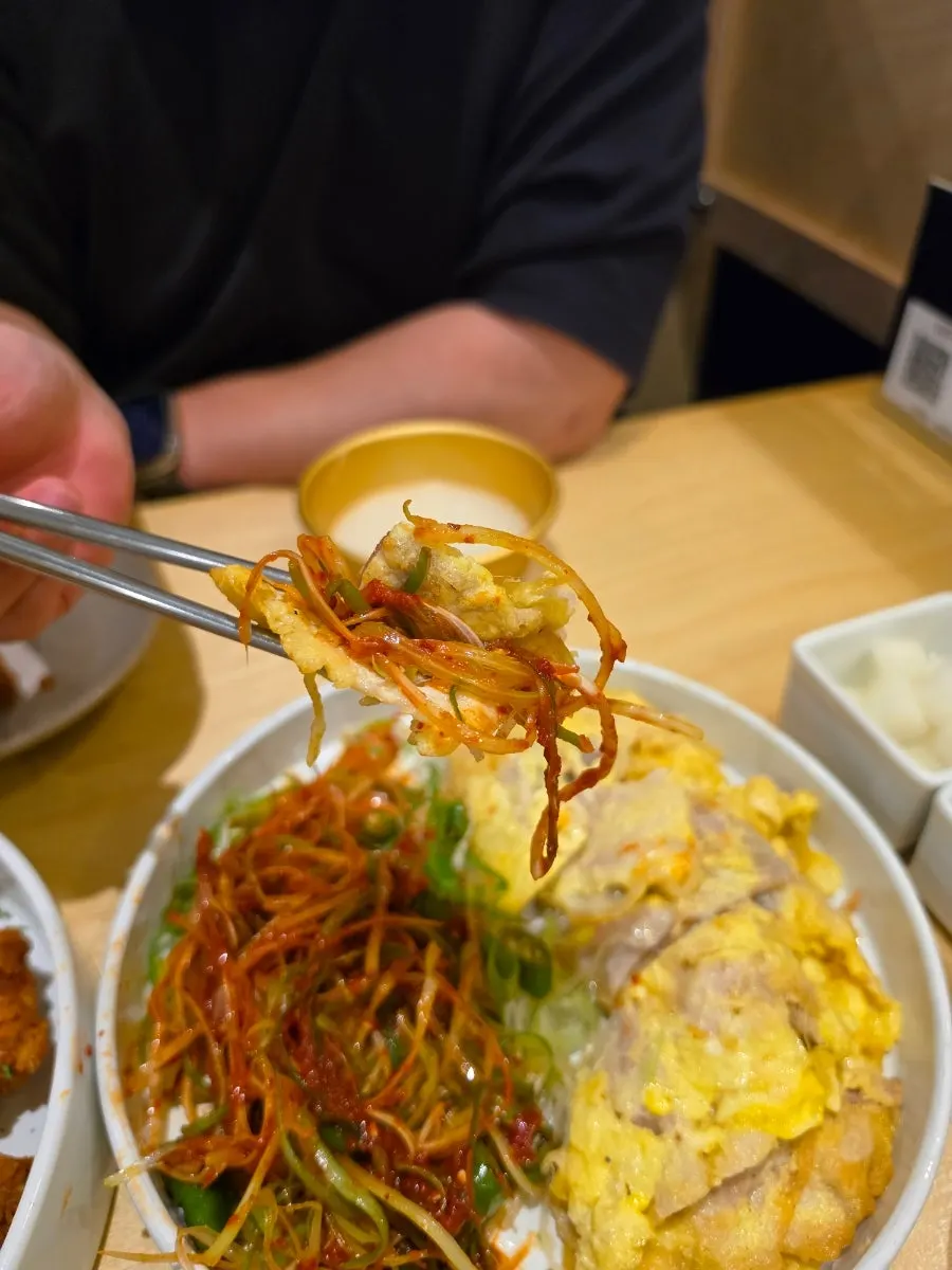 A piece of pork jeon topped with spicy spring onion shreds