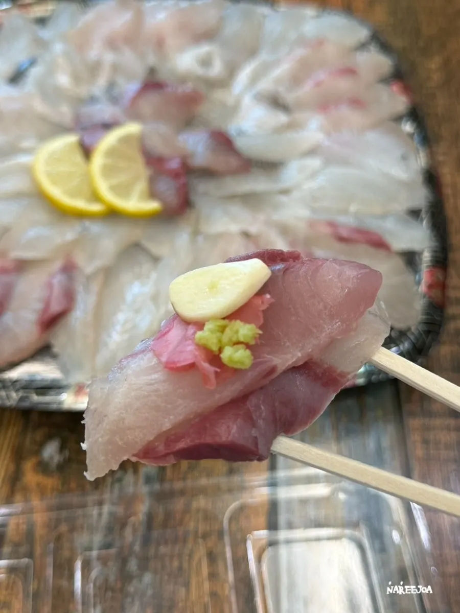 A piece of sashimi picked up with chopsticks