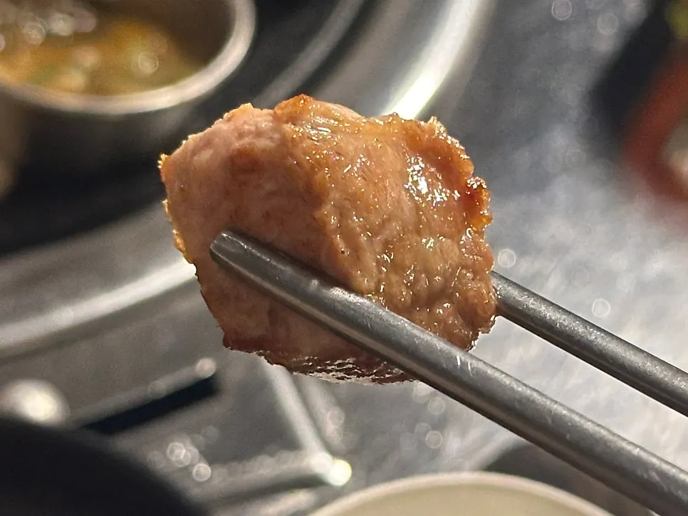 Thick salted pork neck grilled by a staff member