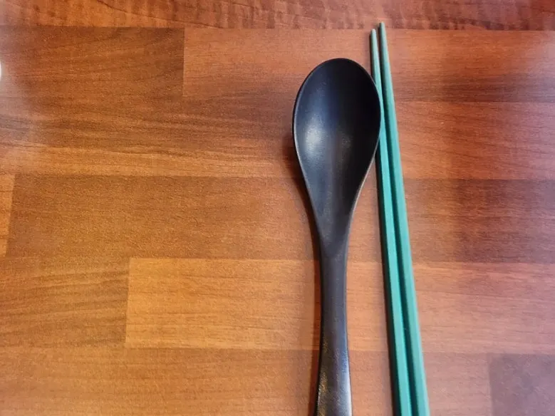 Table set with green chopsticks and a spoon
