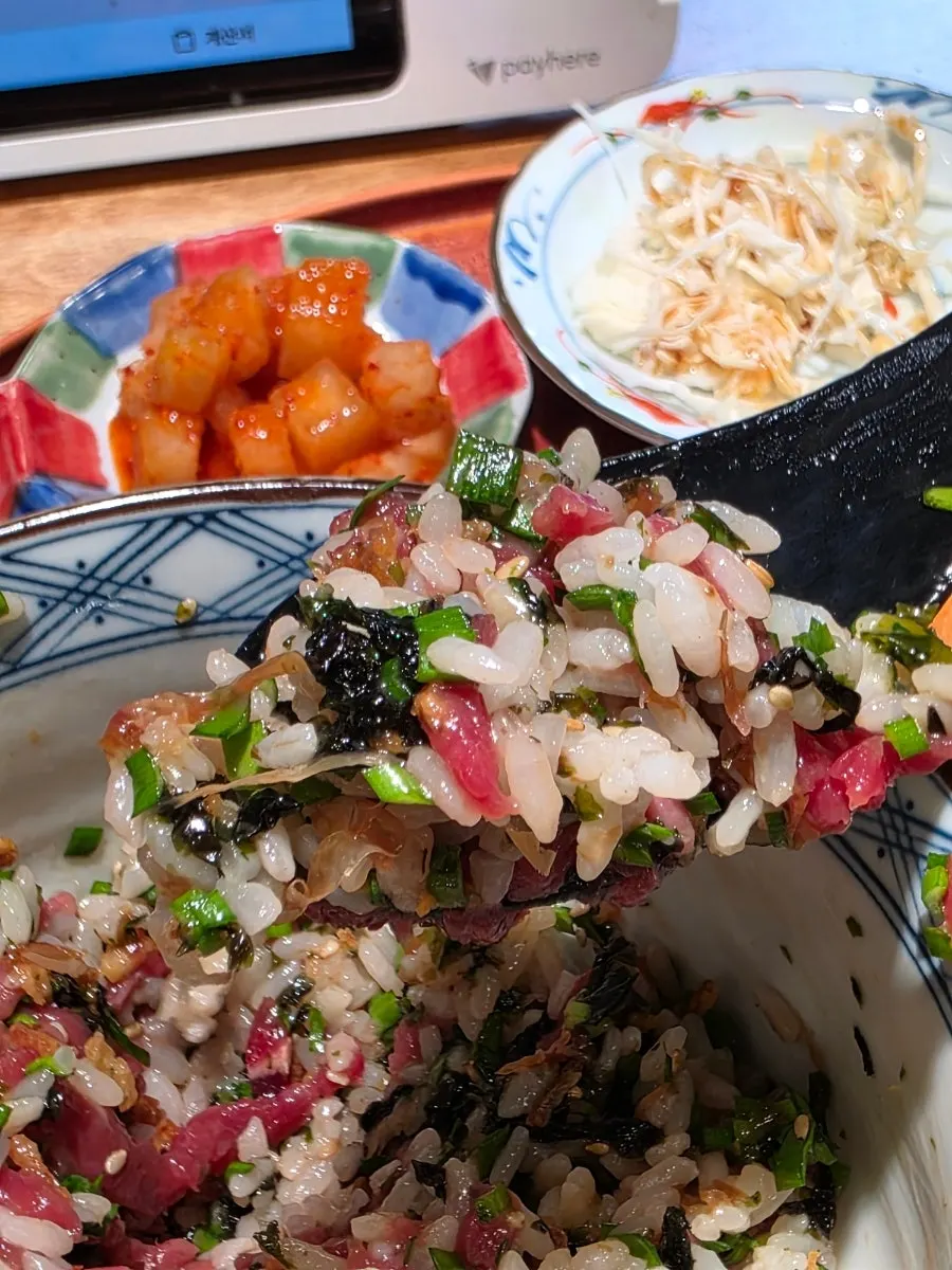 A spoonful of yukhoe rice bowl mixed with egg yolk