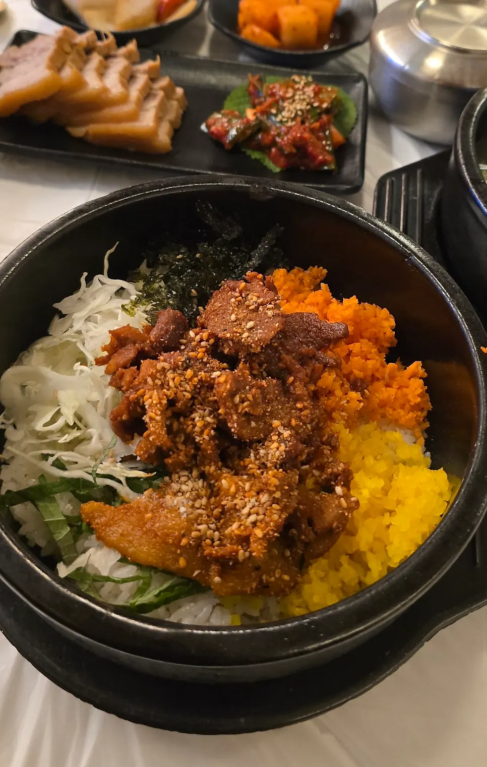 Table spread of galbitang, spicy pork stone pot bibimbap, and mul-makguksu set for one