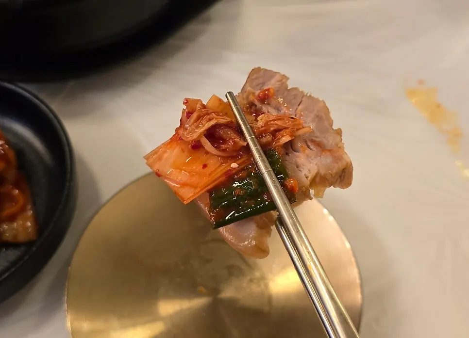 A piece of bossam placed on makguksu noodles