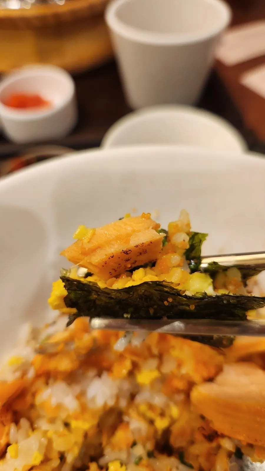 A bite of salmon soboru sotbap wrapped in seaweed