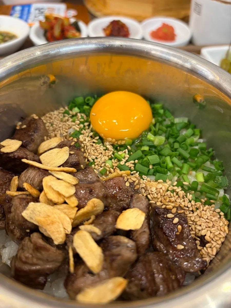Steak pot rice topped with egg yolk and scallions