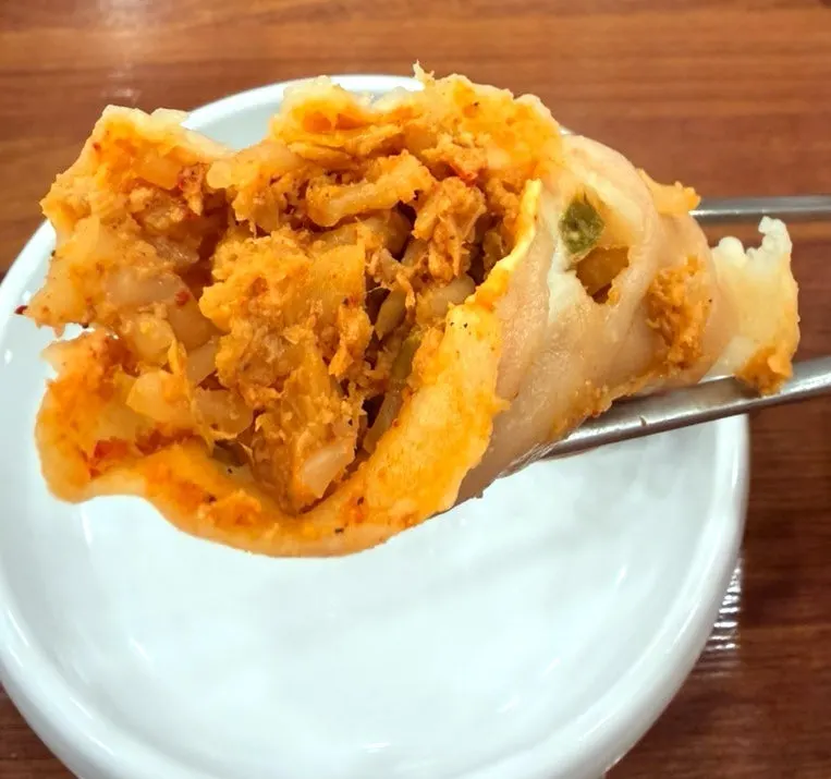 A mandu dipped into the perilla broth