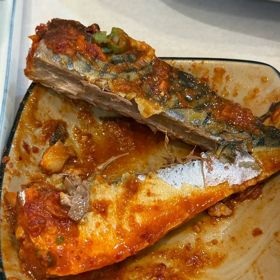 A piece of braised fish pulled apart with chopsticks