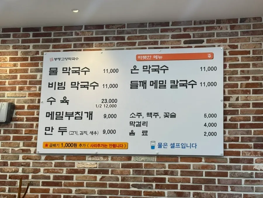 Menu board mounted on the wall at Bongpyeong Gohyang Makguksu