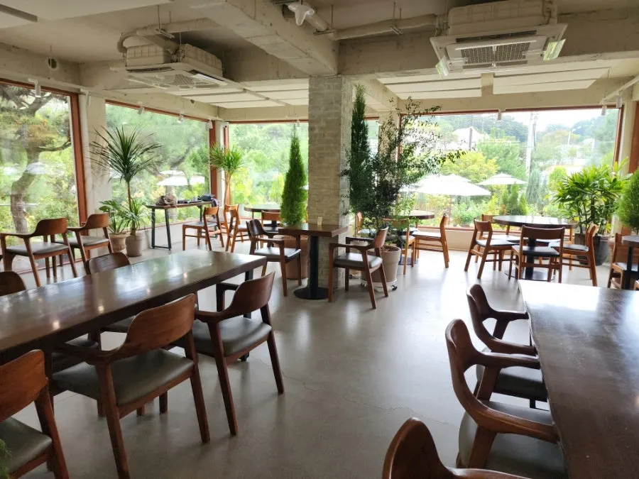1st-floor wood slab table with a garden view through floor-to-ceiling windows