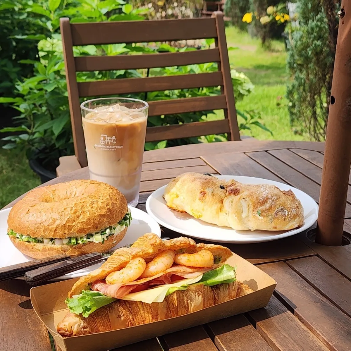 Bread and café latte set out at an outdoor parasol table